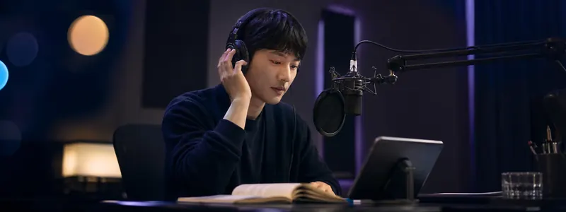 配音演员戴耳机在麦克风前用 IndexTTS2.5 演播有声书，屏幕显示配音文本